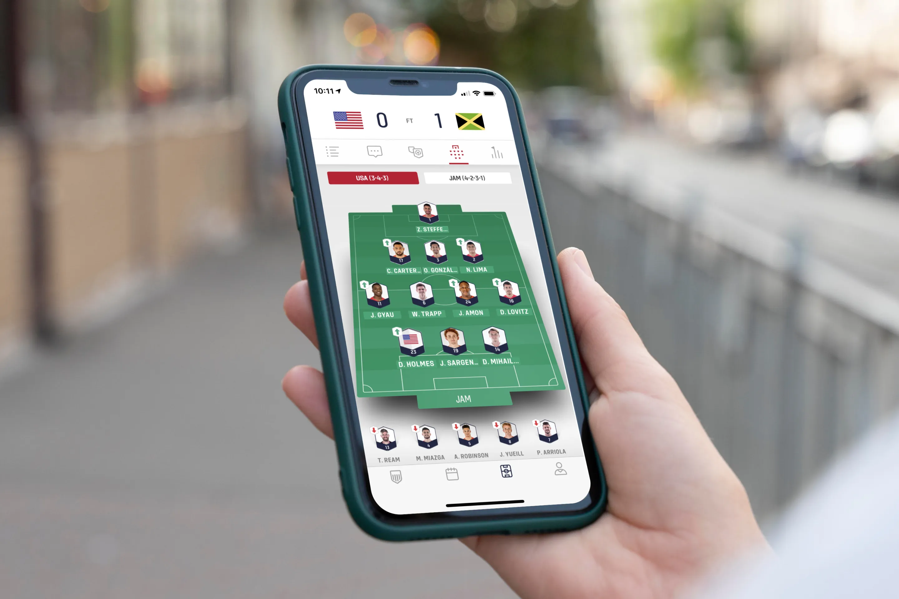 Person holding a phone with the US Soccer app showing the line-up screen showing players’ positions on the pitch